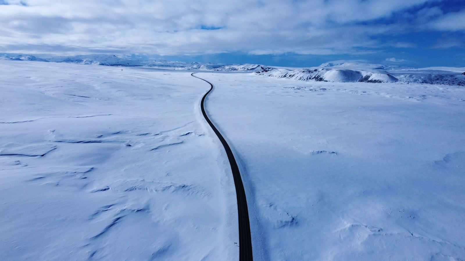 Aerial — lone road through white landscape