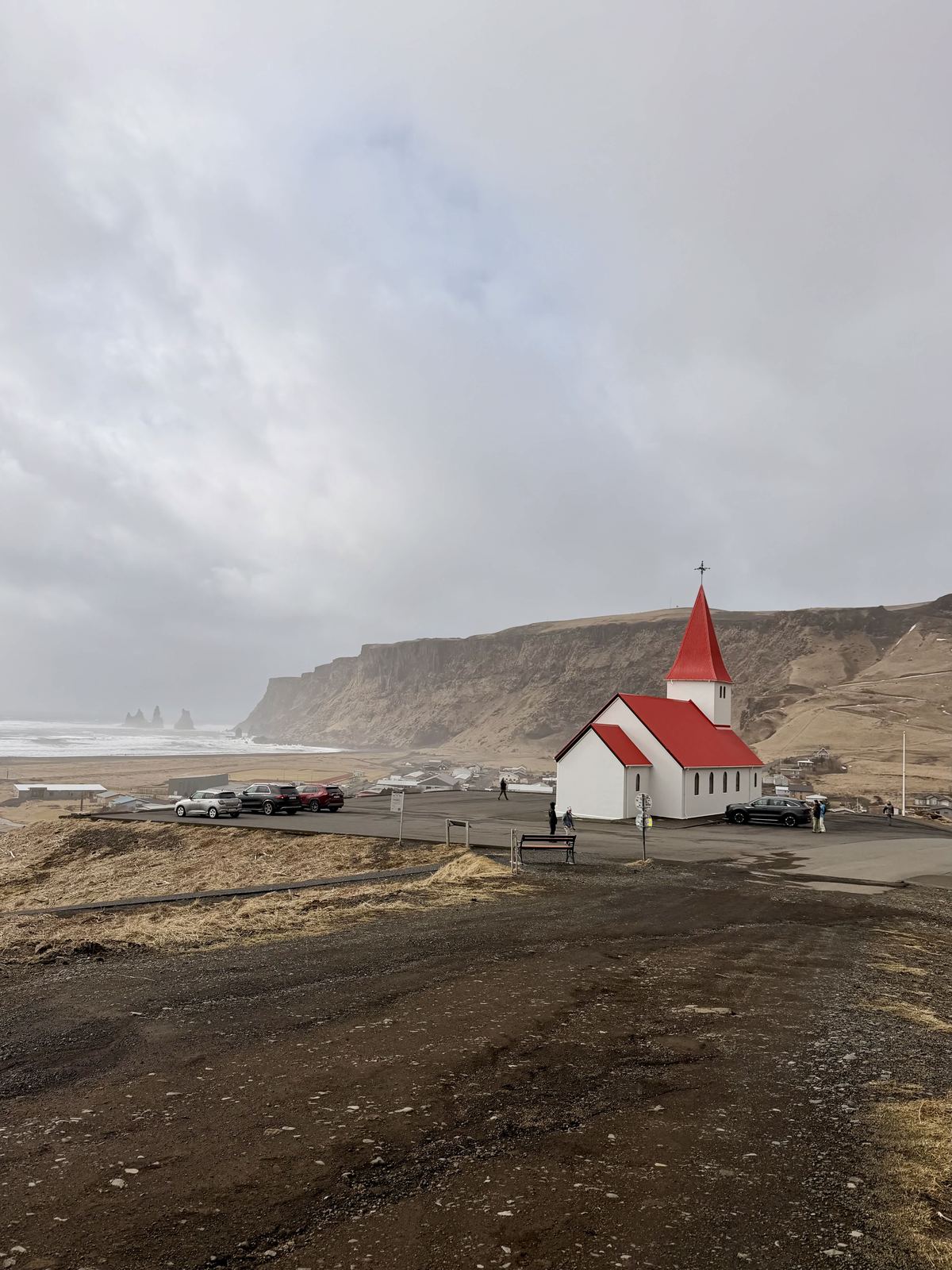 Vik church — white with vivid red roof on the hill, black beach behind