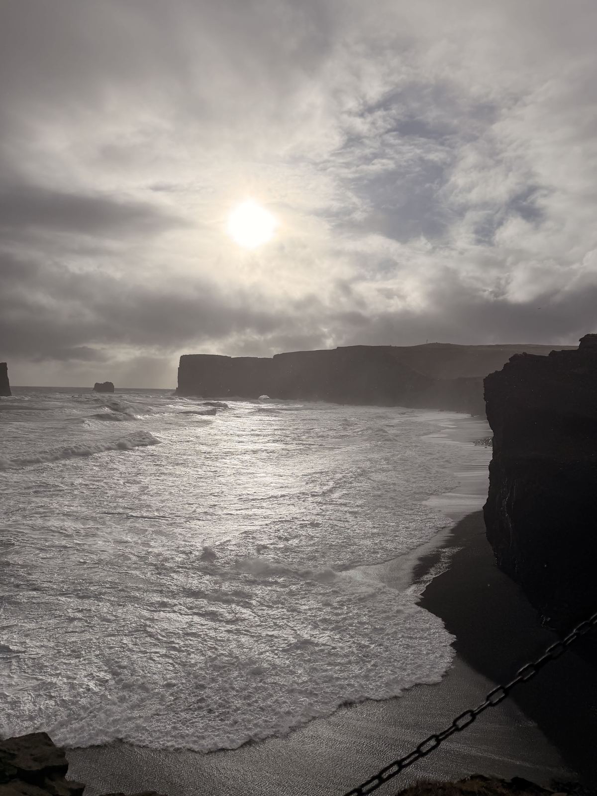 Dyrhólaey — sun breaking through clouds, silver light on the ocean and black cliffs