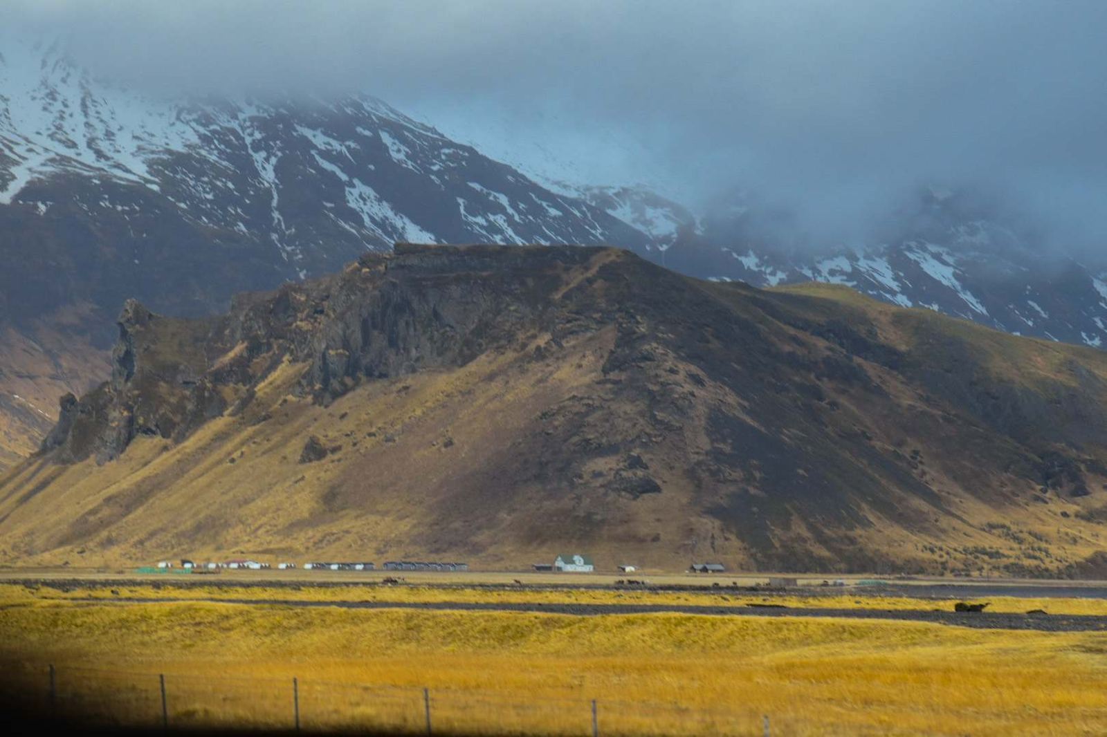 Golden countryside en route — warm fields, dramatic mountain, small farm