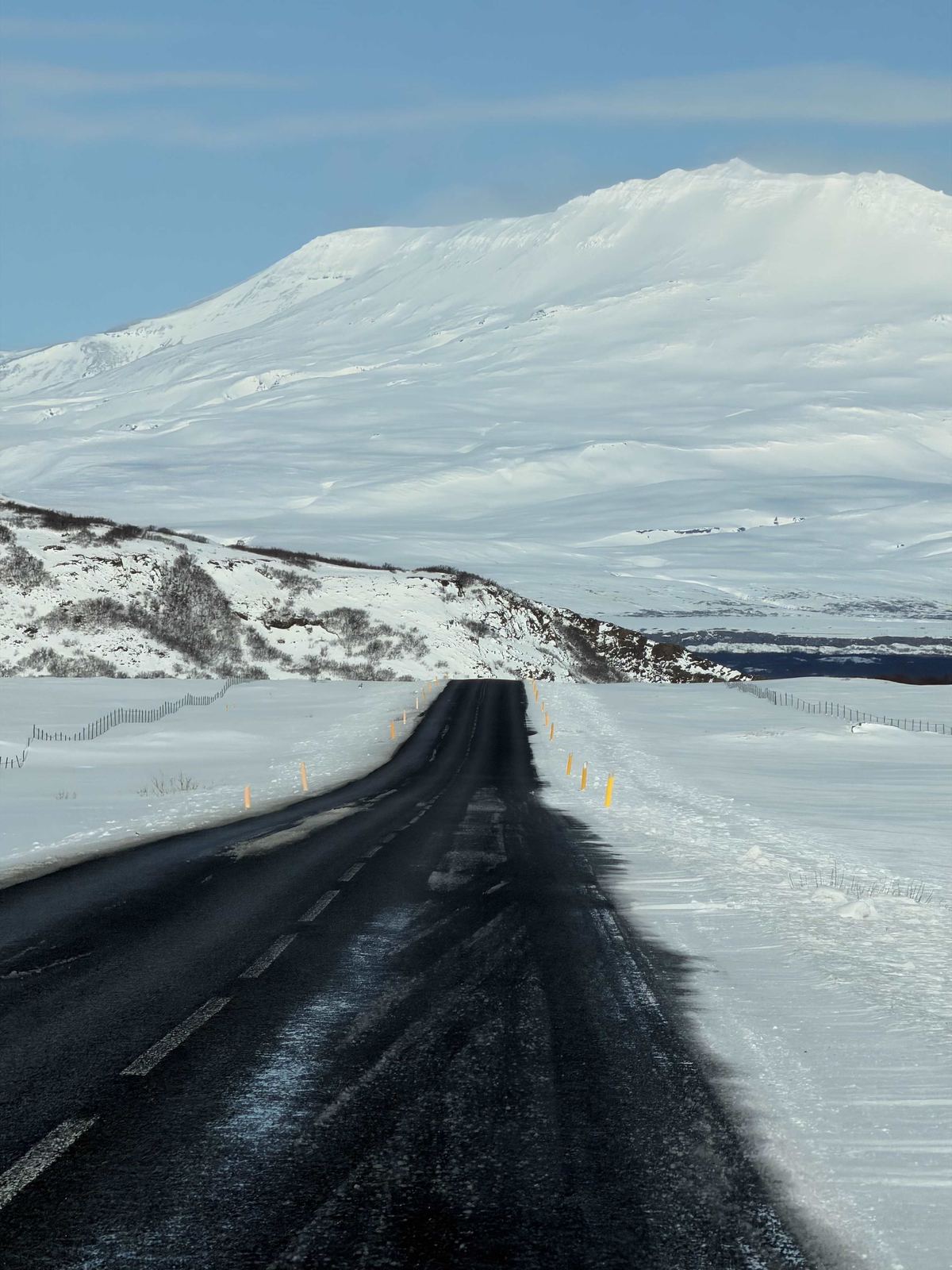 Road back to Reykjavik — straight black road through snow, massive white mountain ahead